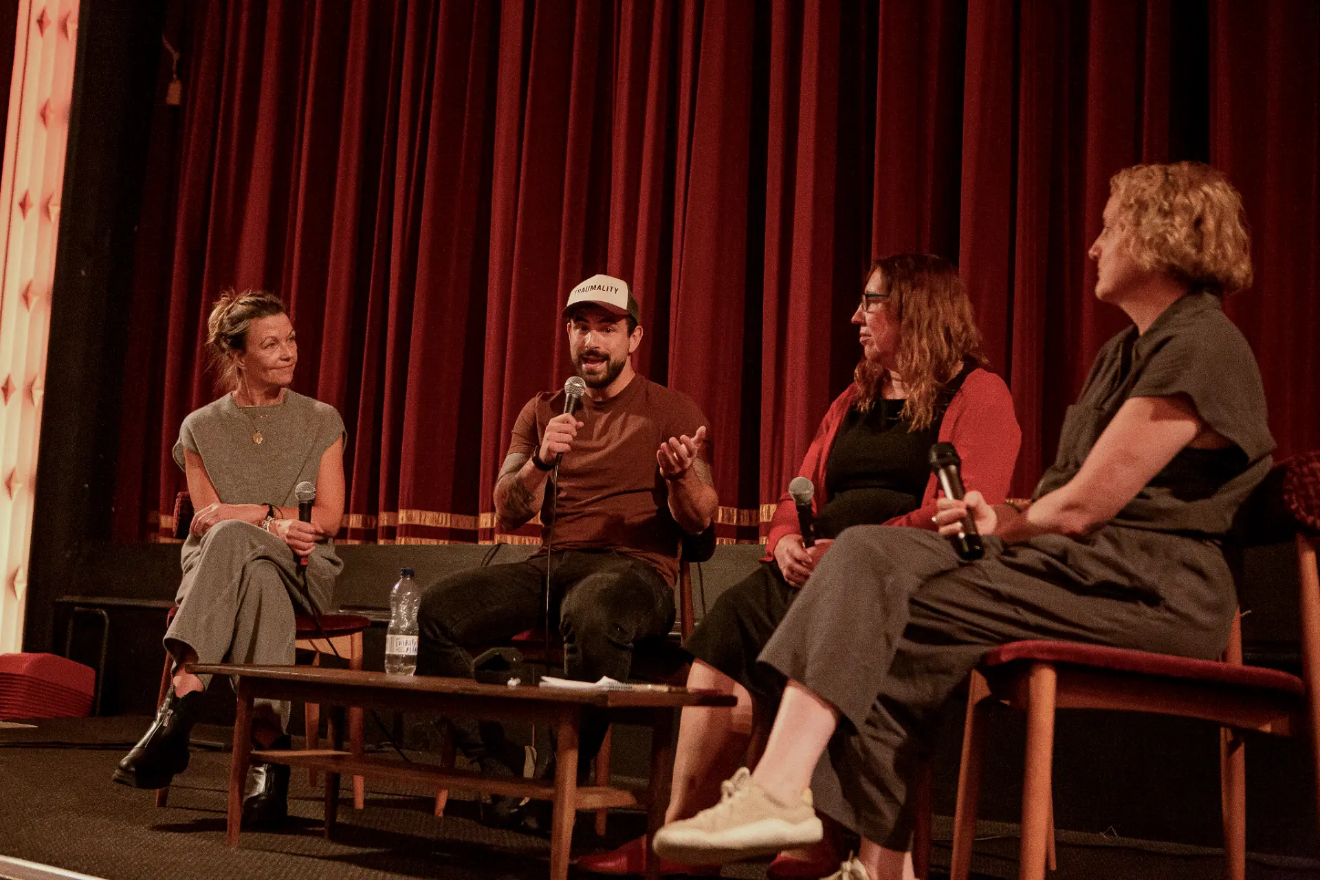 Ton Mazzone speaking into a microphone on stage beside the other panellists